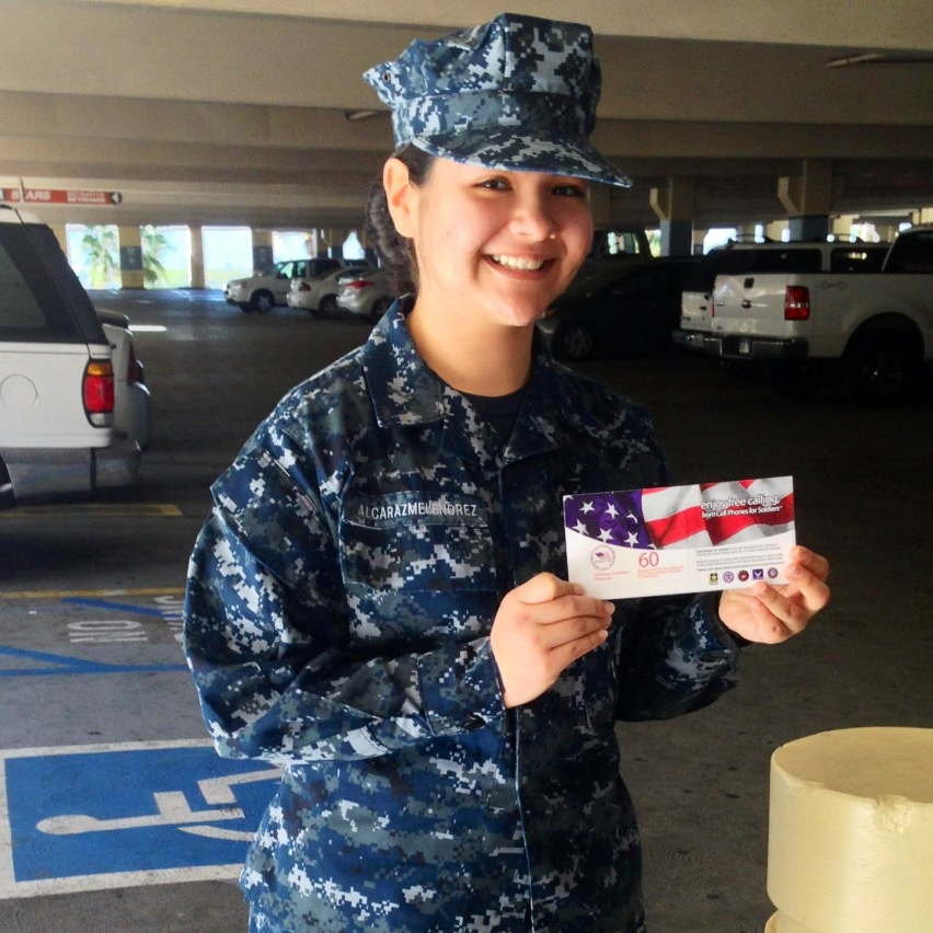 U.S. service member smiling and holding a Cell Phones For Soldiers international calling card.